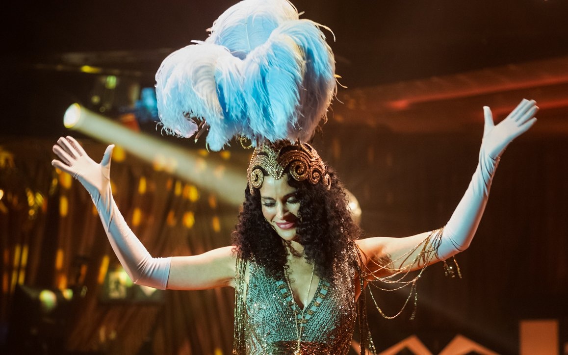 Performer in elaborate costume with feathered headdress at 58th Street show.