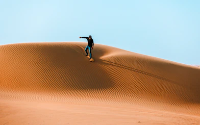 Sandboarding on a dune in Doha desert, Qatar.
