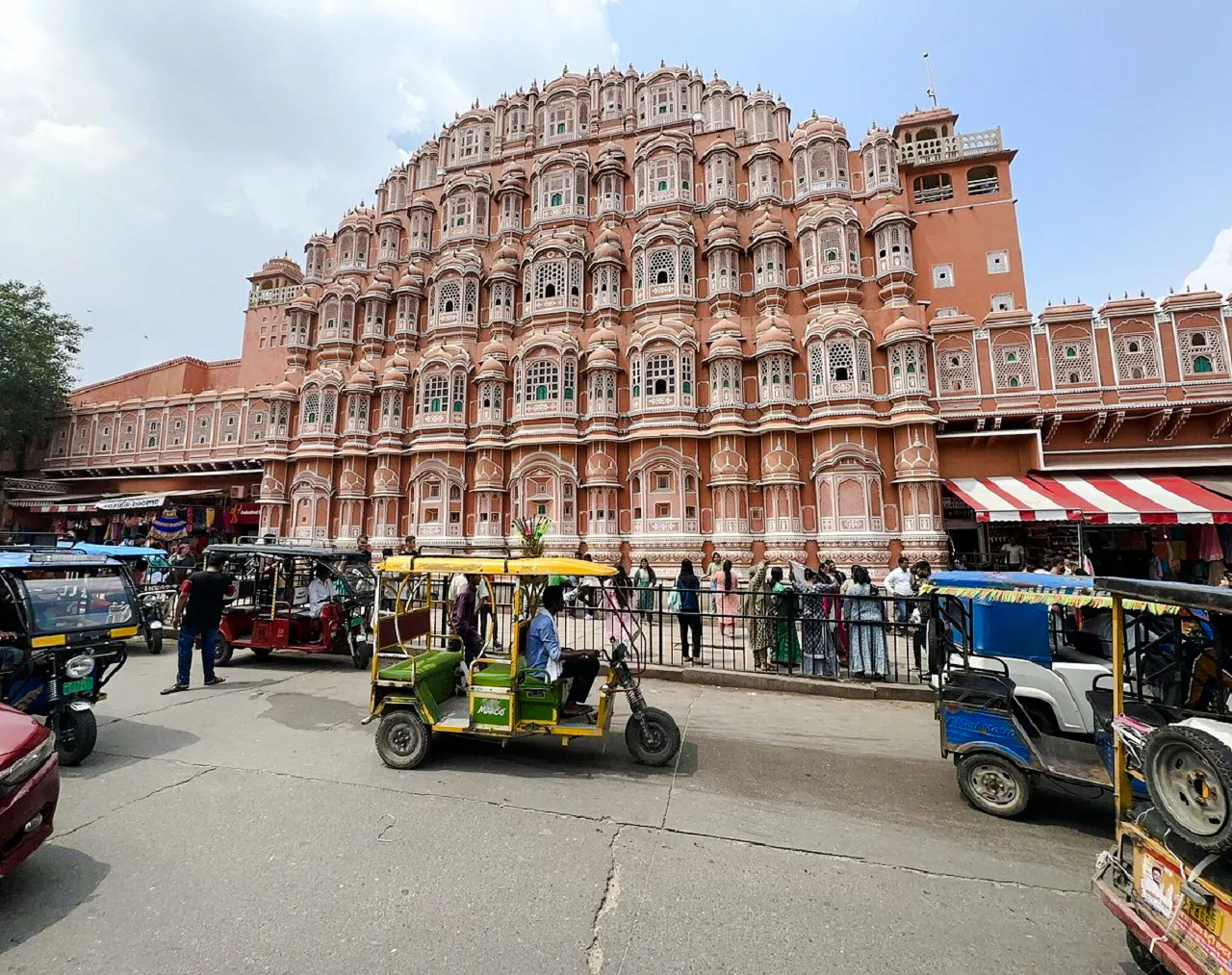 Hawa Mahal facade with rickshaws and visitors in Jaipur.