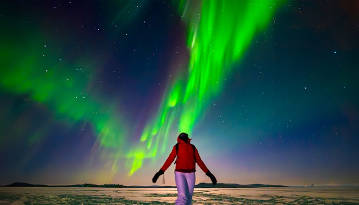 Northern lights illuminating snowy landscape in Rovaniemi during a guided tour.