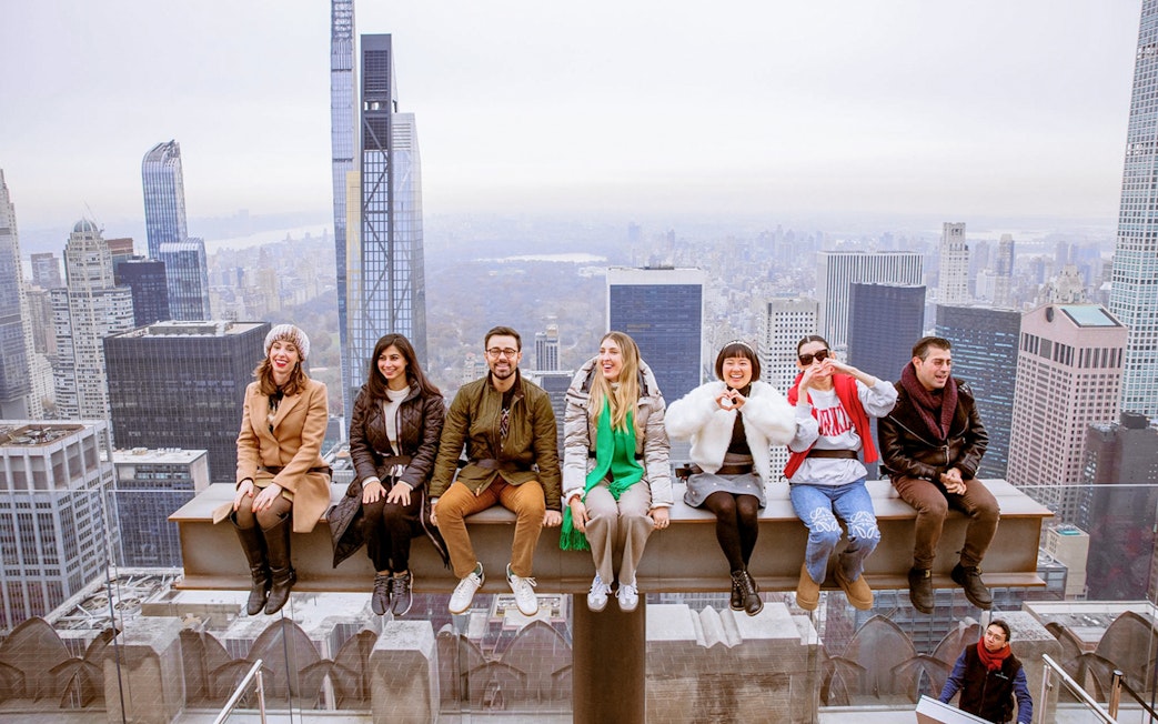 Group enjoying skyline view from Top of the Rock Observation Deck, New York City.
