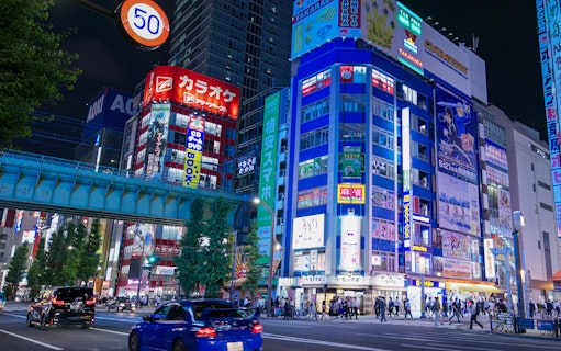 Akihabara street at night with colorful anime and gaming store signs.