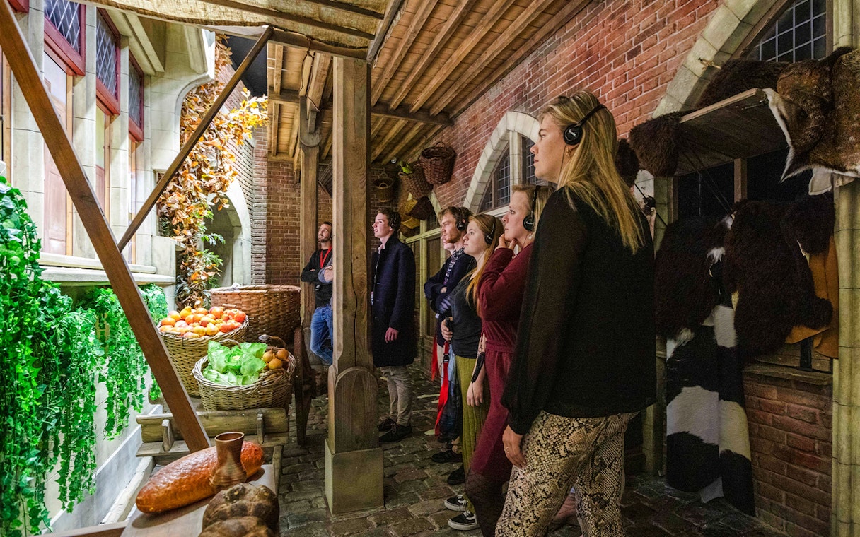 Visitors exploring a medieval market scene at Historium Bruges exhibit.