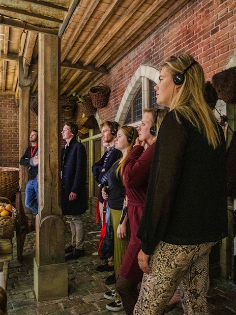 Visitors exploring a medieval market scene at Historium Bruges exhibit.