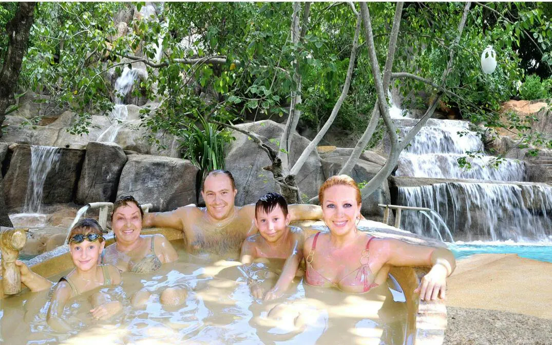 Family enjoying a natural hot spring with waterfall backdrop, Cai River View, Dubai.