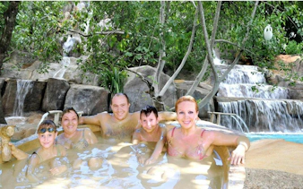 Family enjoying a natural hot spring with waterfall backdrop, Cai River View, Dubai.