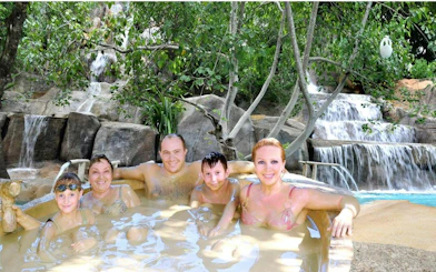 Family enjoying a natural hot spring with waterfall backdrop, Cai River View, Dubai.