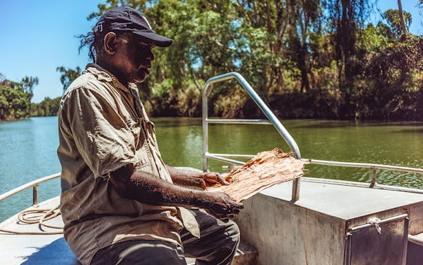 Man on a boat holding bark during Kakadu Cultural Cruise, Australia.