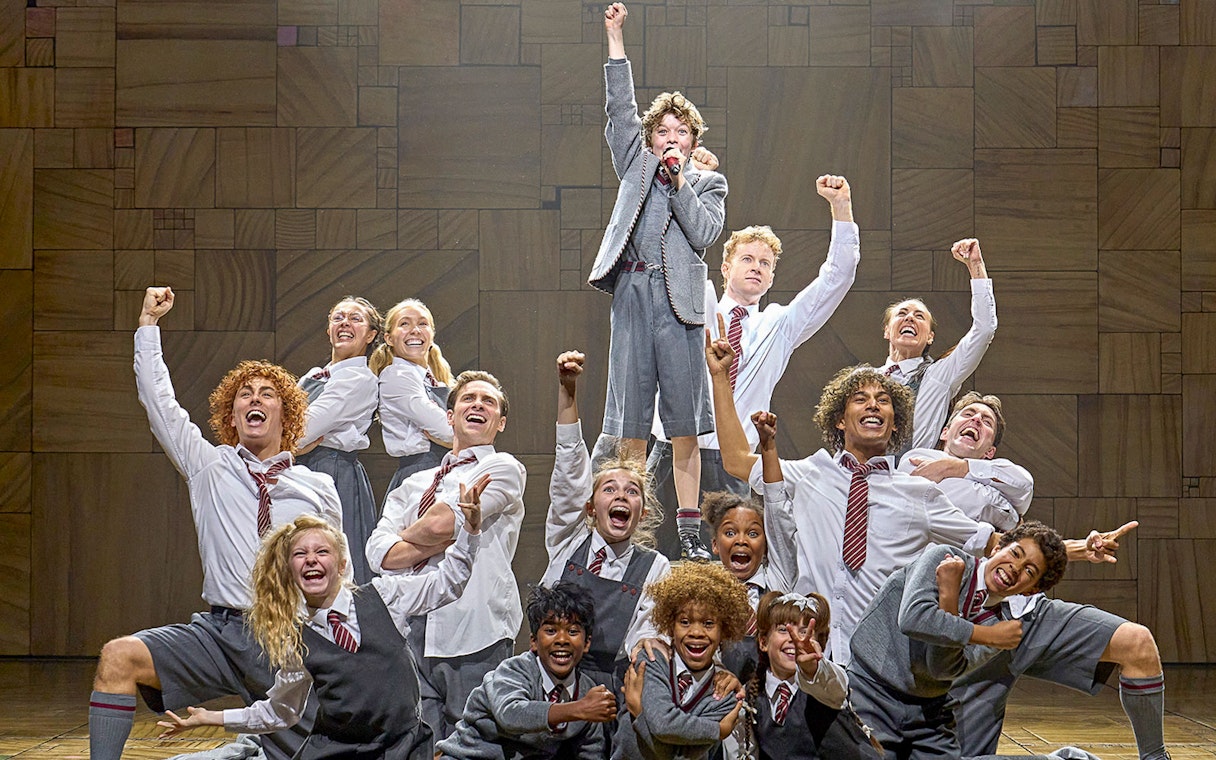 Cast of Matilda The Musical performing on stage with raised fists.
