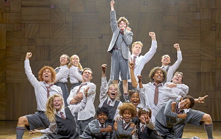 Cast of Matilda The Musical performing on stage with raised fists.