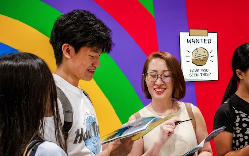 Participants engaging in RANSACK PUZZLE HUNT: The Meltdown Menace, examining clues against a colorful backdrop.