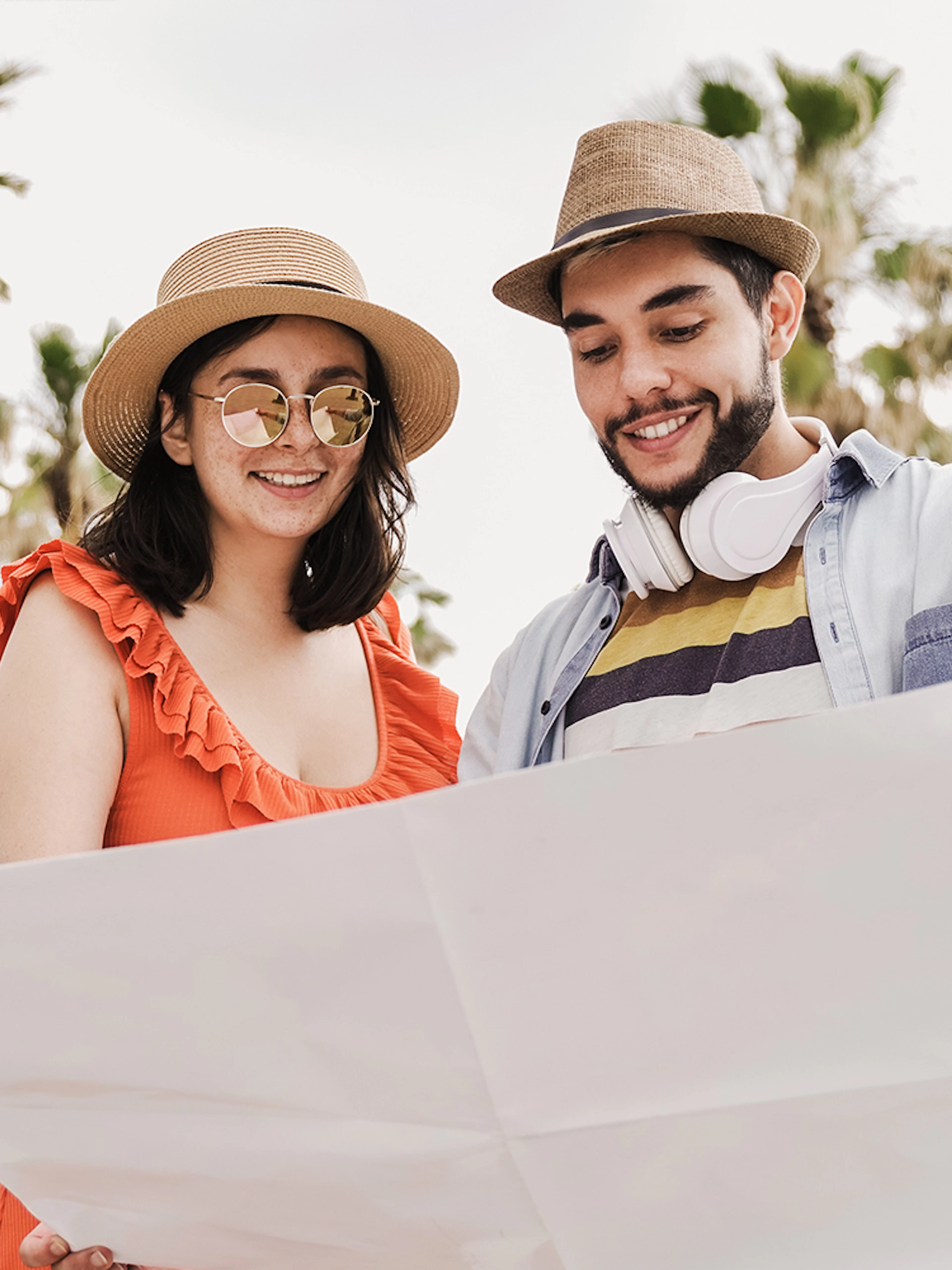 Couple examining a map in Barcelona with palm trees in the background.