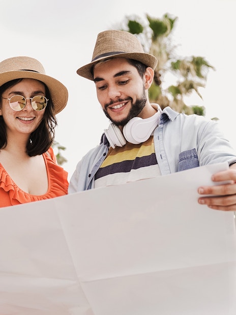 Couple examining a map in Barcelona with palm trees in the background.