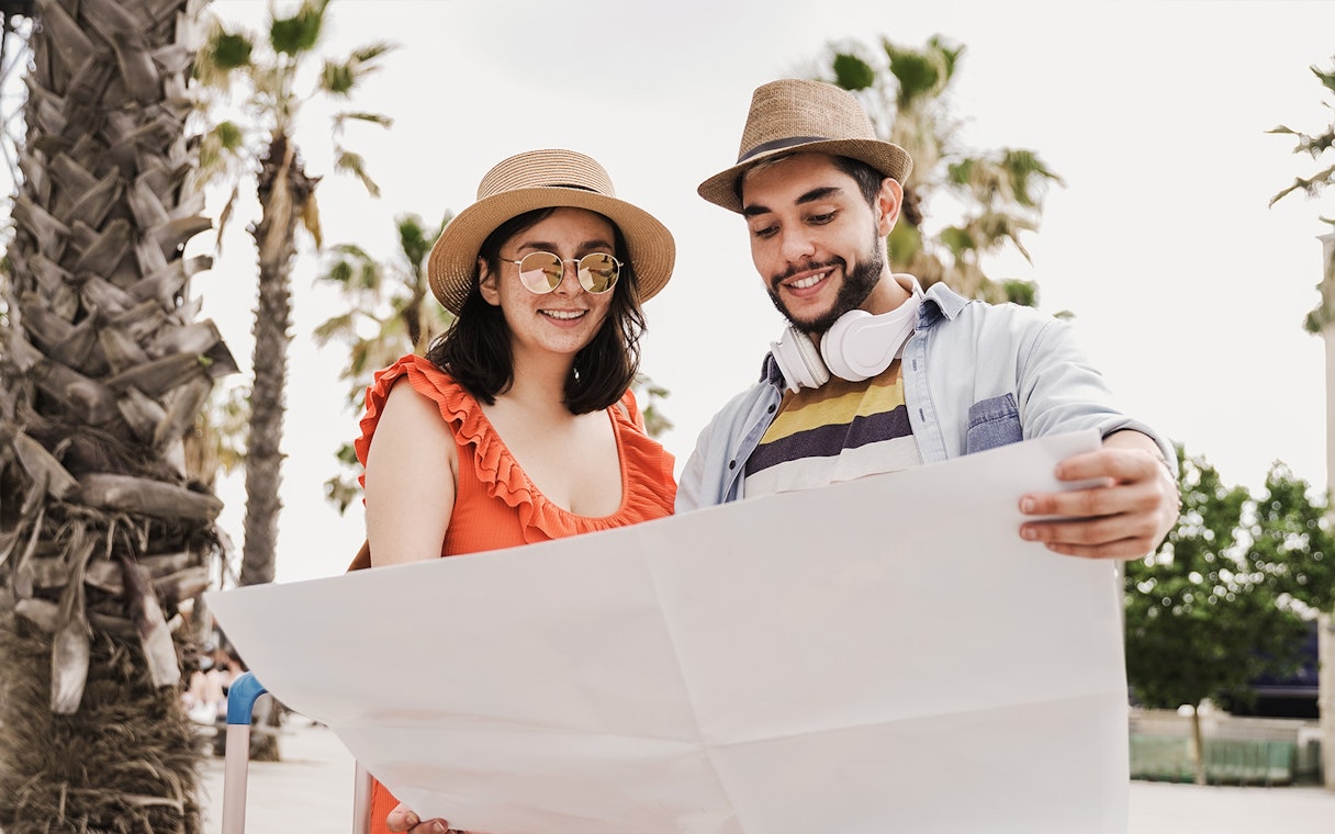 Couple examining a map in Barcelona with palm trees in the background.