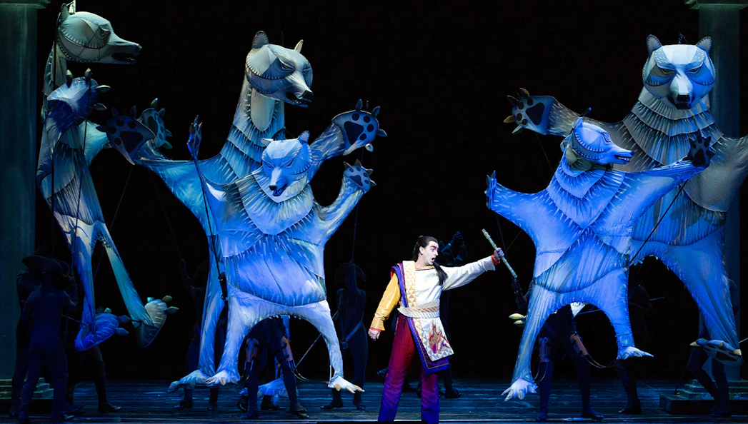Performer with large animal puppets in The Magic Flute opera scene.