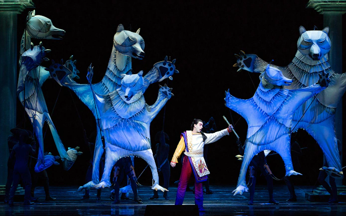 Performer with large animal puppets in The Magic Flute opera scene.