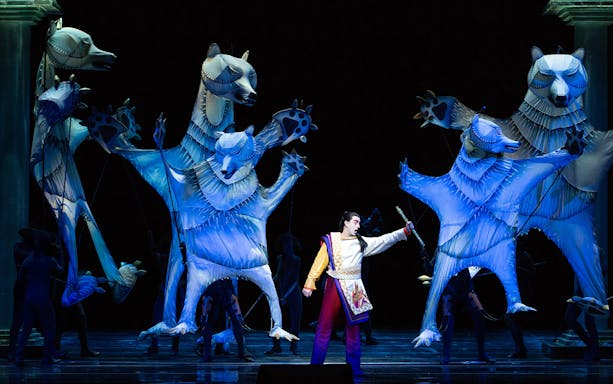 Performer with large animal puppets in The Magic Flute opera scene.