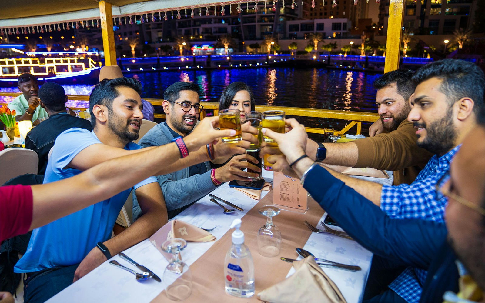 Dhow boat on Dubai Creek with guests dining and enjoying live entertainment.