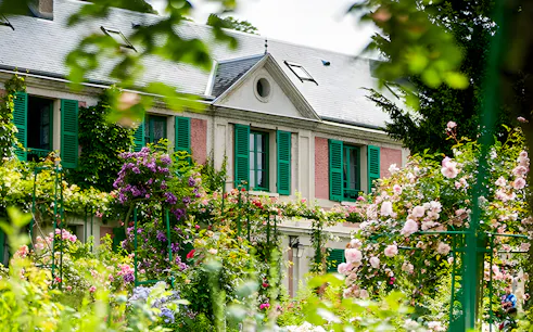 Monet's house with green shutters surrounded by blooming gardens in Giverny.