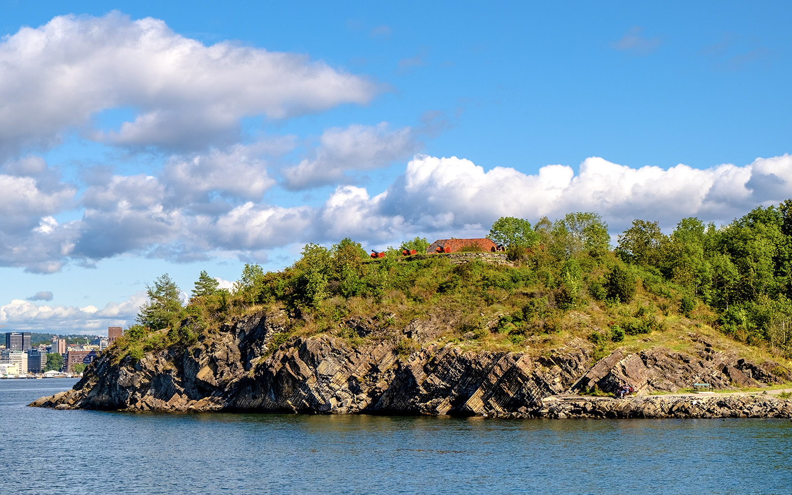 Panoramic view of Hovedøya island with rocky shoreline and lush greenery.