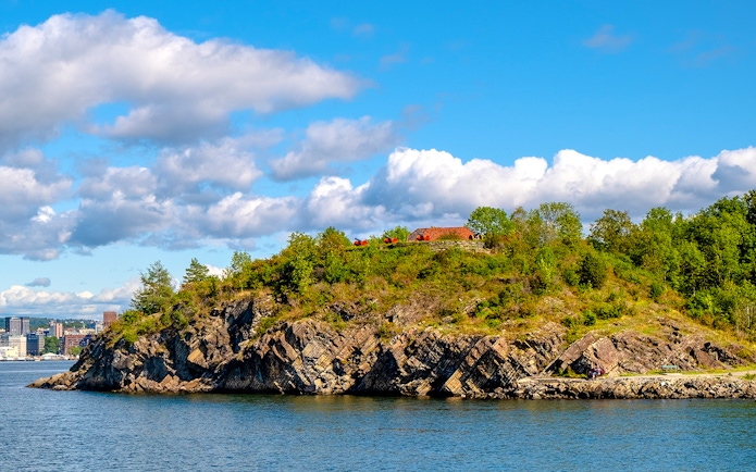 Panoramic view of Hovedøya island with rocky shoreline and lush greenery.
