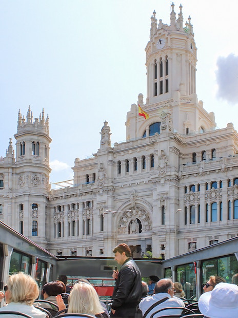 Open-top bus tour passing by the Palacio de Cibeles in Madrid.