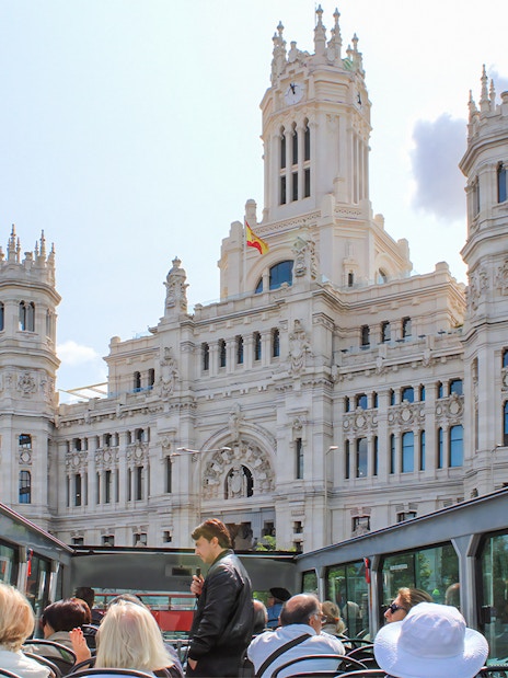 Open-top bus tour passing by the Palacio de Cibeles in Madrid.