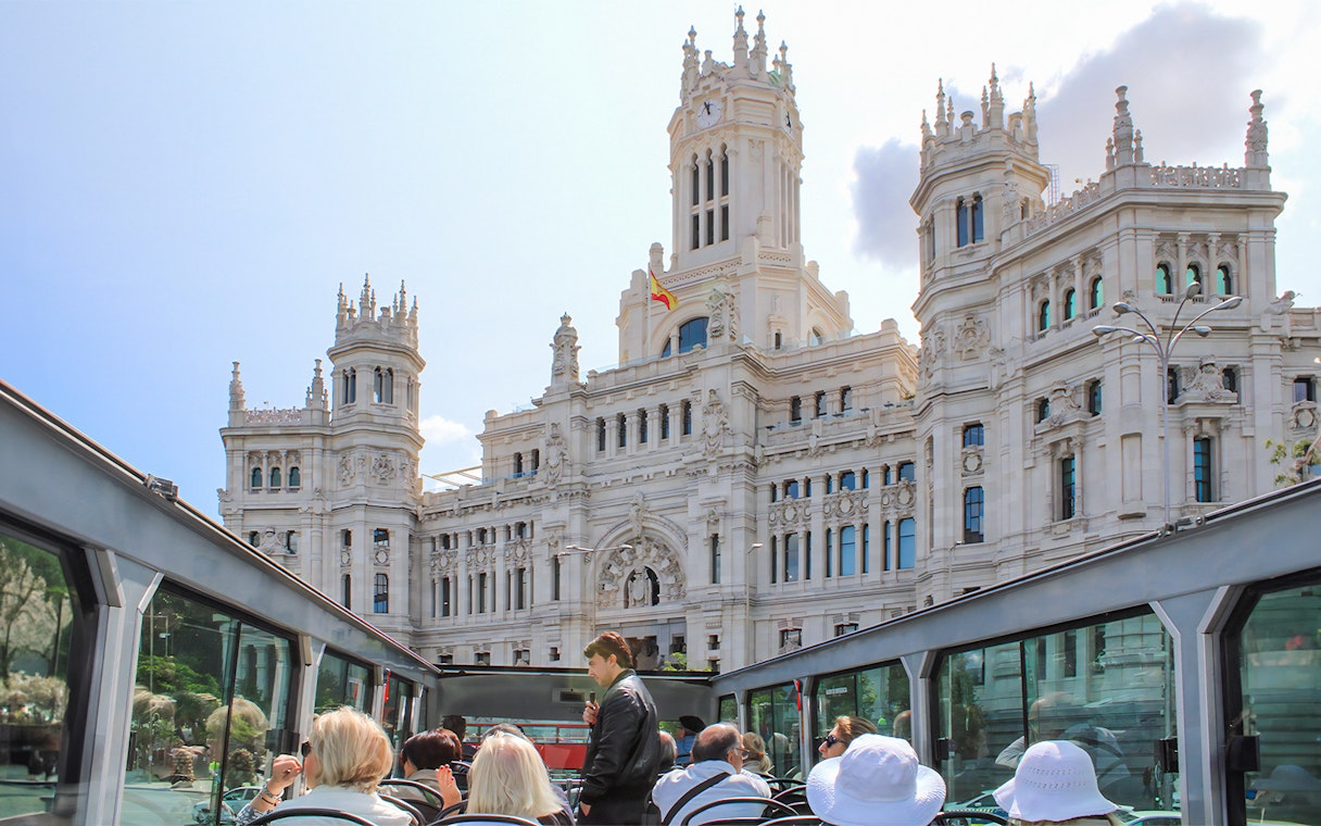 Open-top bus tour passing by the Palacio de Cibeles in Madrid.