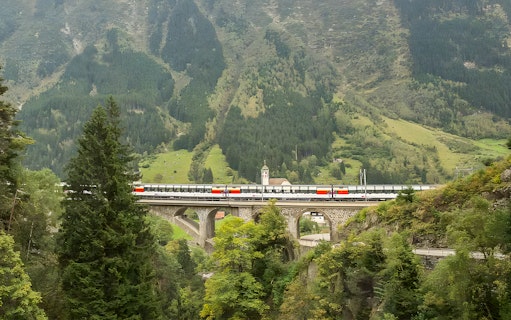 Train crossing a bridge in the Swiss Alps on the Gotthard Panorama Express route.