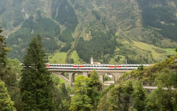 Train crossing a bridge in the Swiss Alps on the Gotthard Panorama Express route.