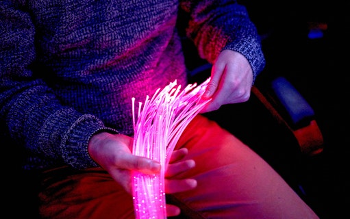 Person holding glowing fiber optic cables at The Tube in Copenhagen.