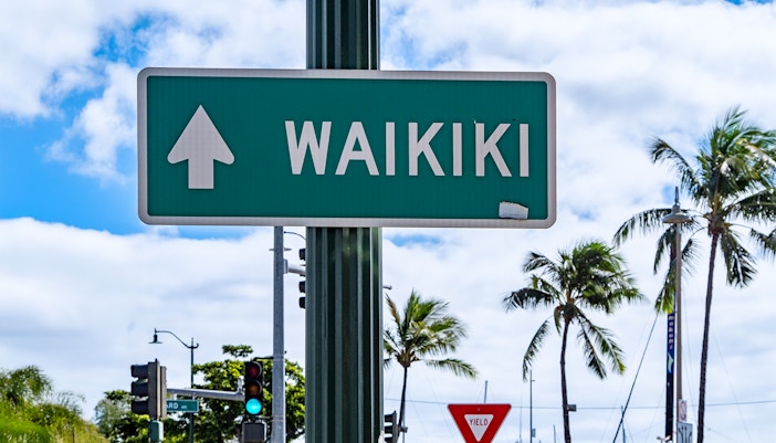 Waikiki direction sign with palm trees in Honolulu, Oahu Island, Hawaii.