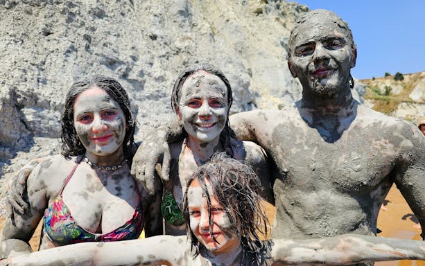 Group covered in clay at Xi Beach, Kefalonia during Dreamy Cruise tour.
