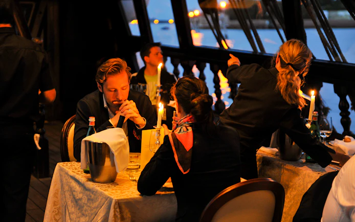 Dinner guests on a Galleon Cruise in Venice with candlelit tables and water views.