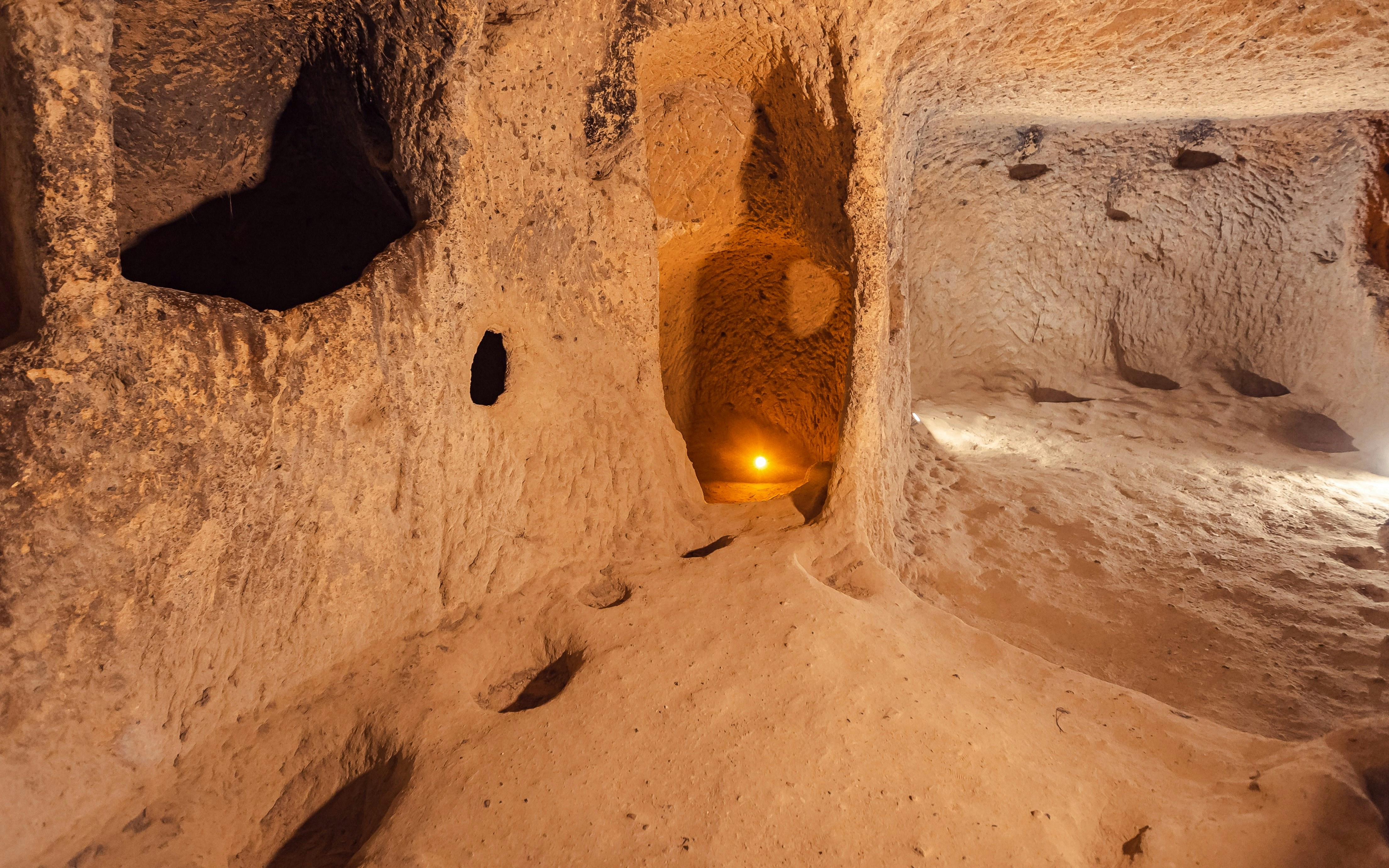 Ozkonak underground city tunnel with carved stone walls and dim lighting.