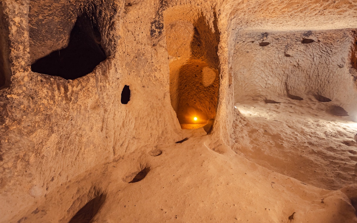 Ozkonak underground city tunnel with carved stone walls and dim lighting.