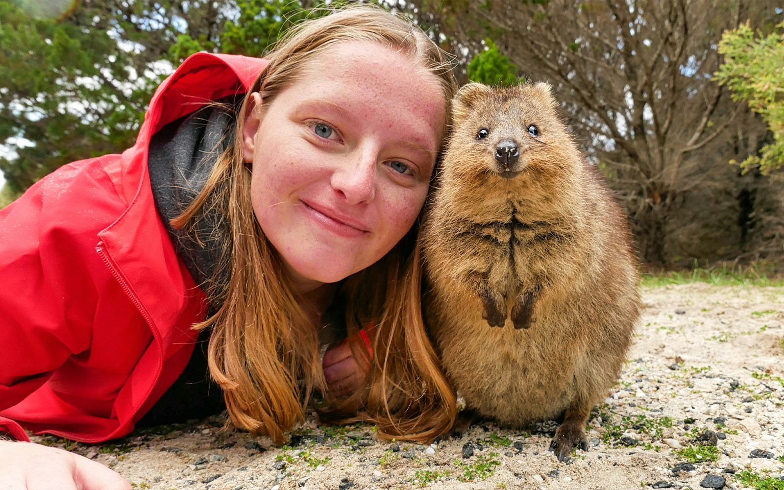 Person smiling with a quokka on Rottnest Island during a ferry and adventure boat tour.