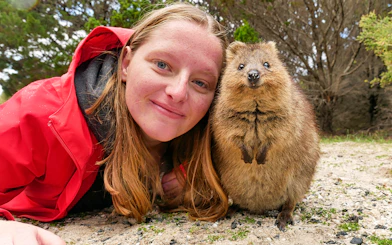 Person smiling with a quokka on Rottnest Island during a ferry and adventure boat tour.