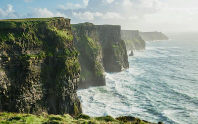 Cliffs of Moher in Ireland with waves crashing against the rocky shoreline.