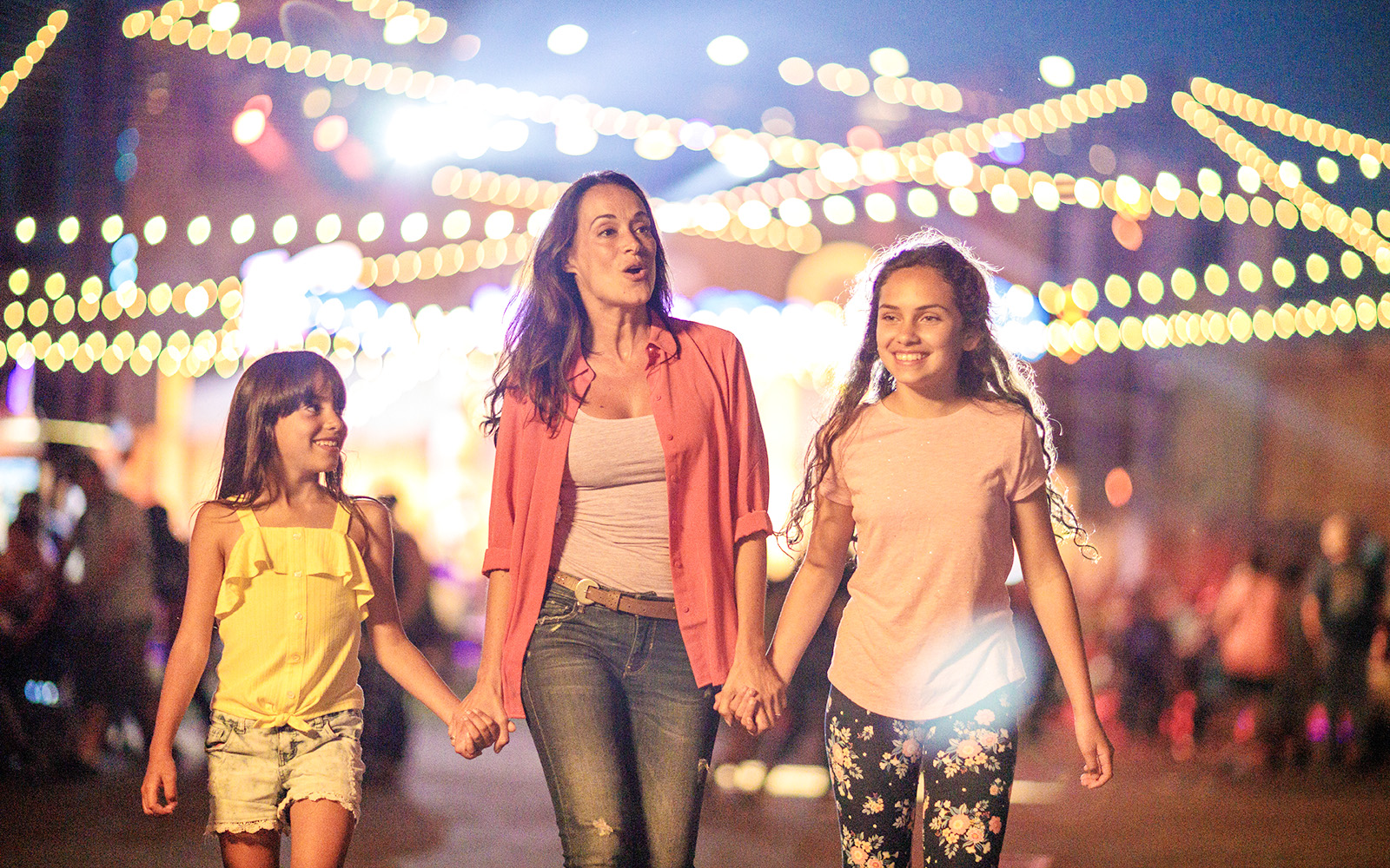 Family enjoying Knott's Summer Nights at Knott's Berry Farm under festive lights.