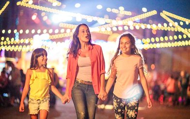 Family enjoying Knott's Summer Nights at Knott's Berry Farm under festive lights.
