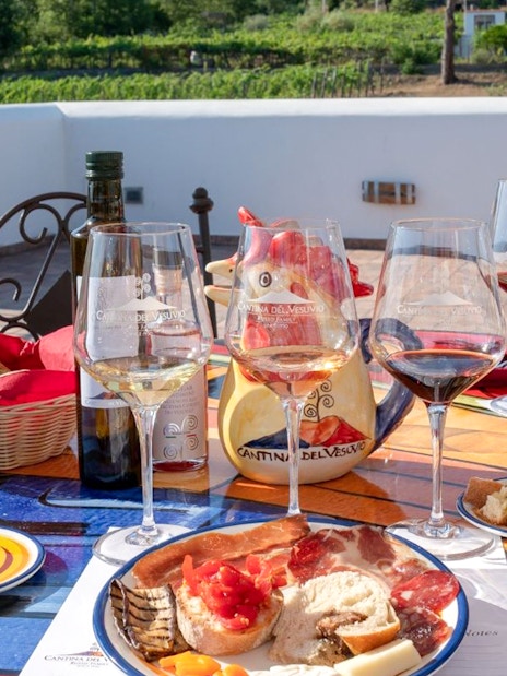 Wine tasting setup with glasses and antipasti on a terrace in Naples vineyard.