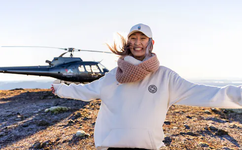 Helicopter on Mount Tarawera summit with smiling visitor during guided tour.