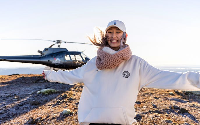 Helicopter on Mount Tarawera summit with smiling visitor during guided tour.