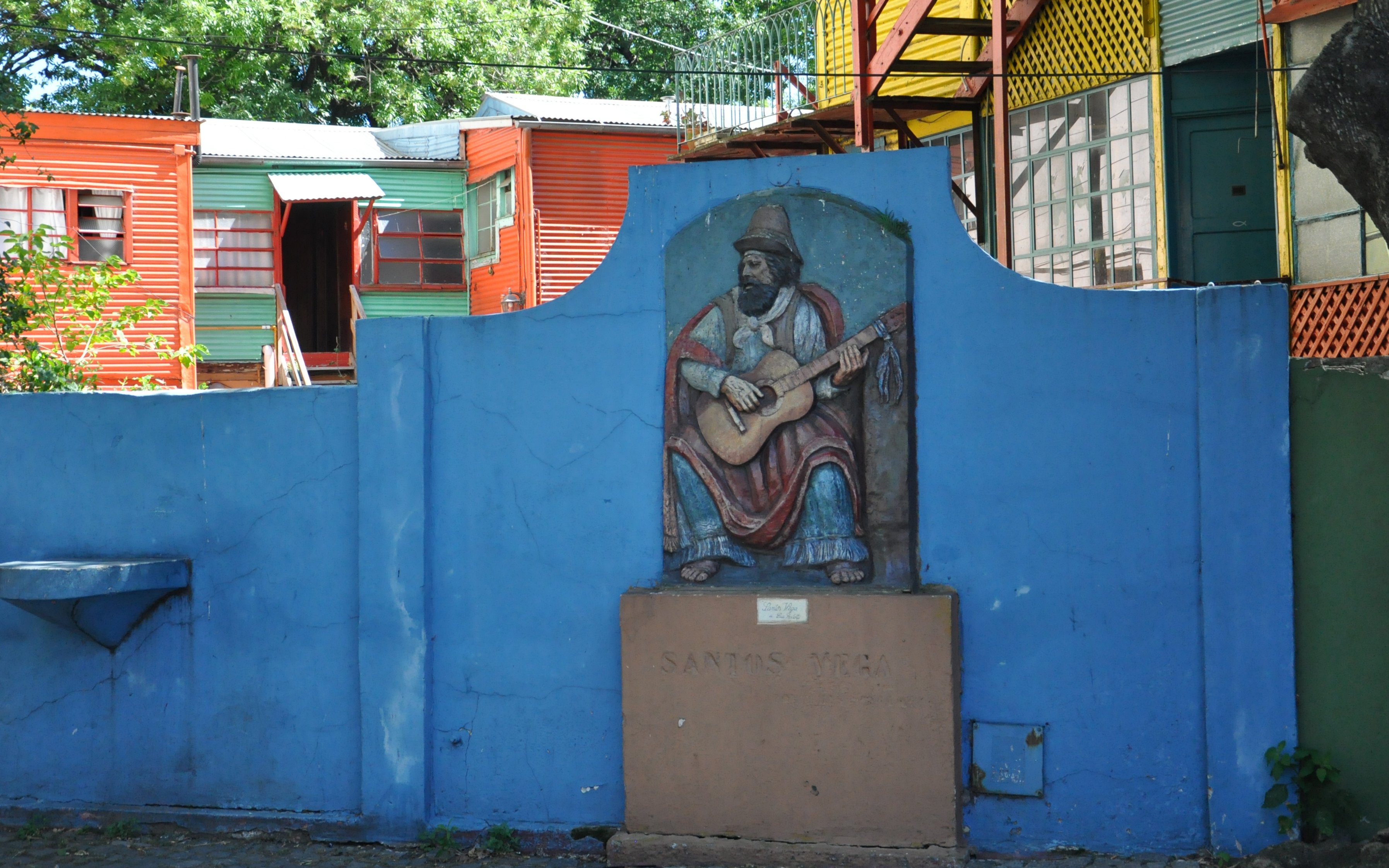 Colorful buildings and mural of a guitarist in Caminito, La Boca, Buenos Aires.