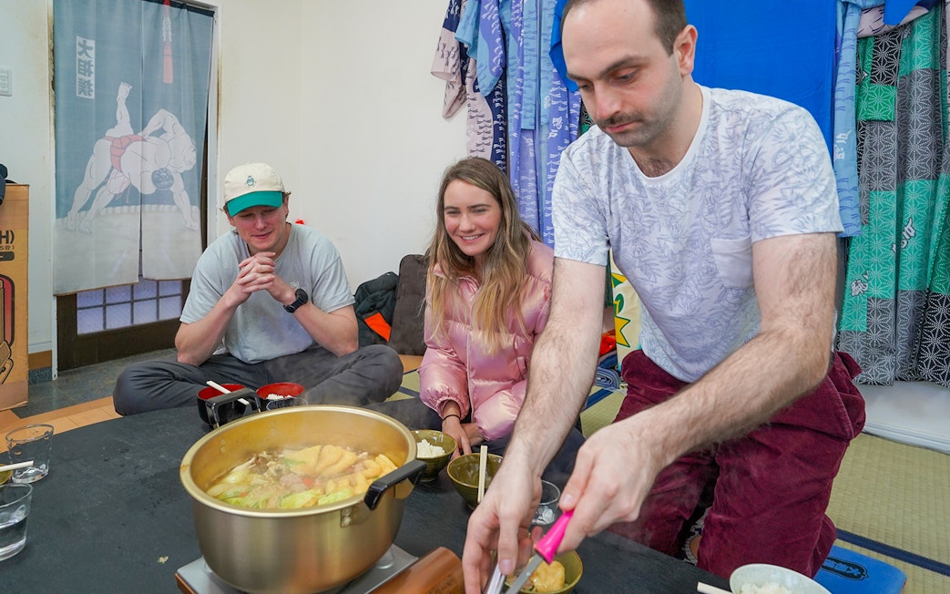 Sumo Wrestling Experience in Tokyo with participants enjoying traditional hot pot meal.