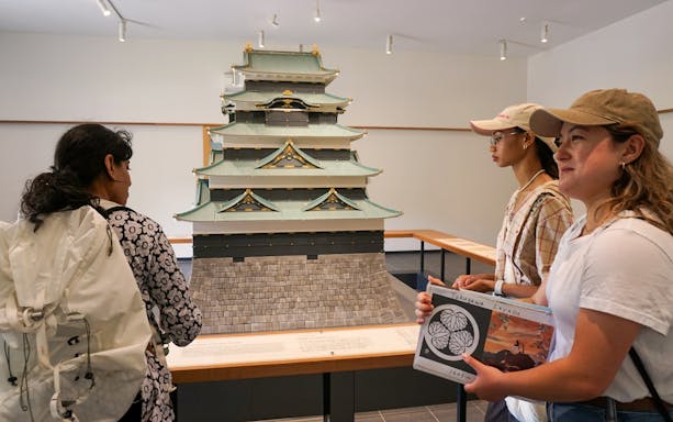 Visitors observing a model of a Japanese castle at the Imperial Palace exhibit.