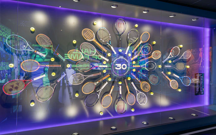 Tennis racket display at Rafa Nadal Museum featuring historic rackets and tennis balls.