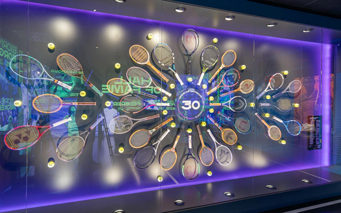 Tennis racket display at Rafa Nadal Museum featuring historic rackets and tennis balls.