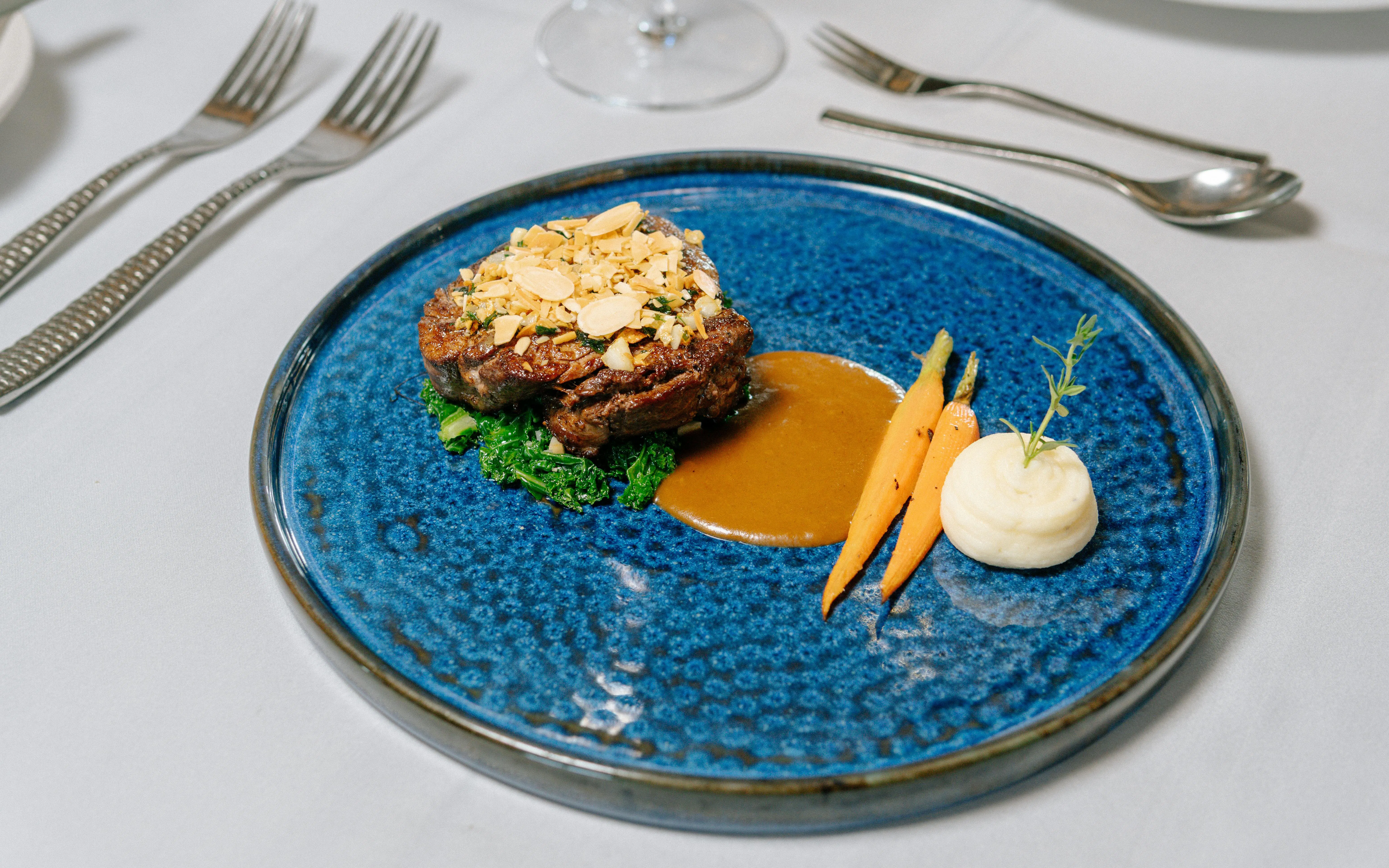 Gourmet meal served on Ha Long Bay 5-star cruise, featuring steak, carrots, and mashed potatoes.